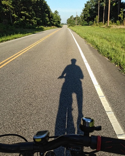 Generic cyclist shadow on rural roadway (Credit: from pixabay public domain images)