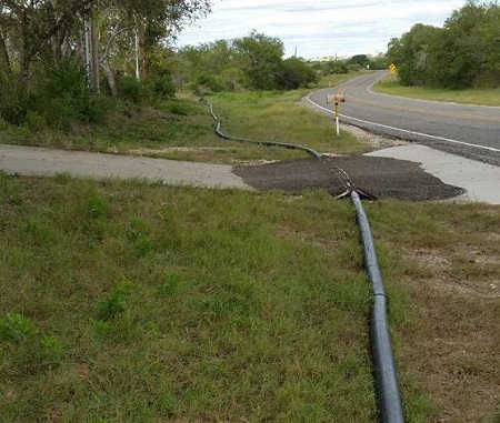 Temporary pipeline ramp using asphalt at low point in right-of-way.